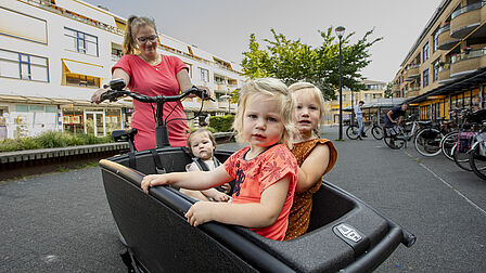 Een vrouw met een bakfiets en drie kinderen